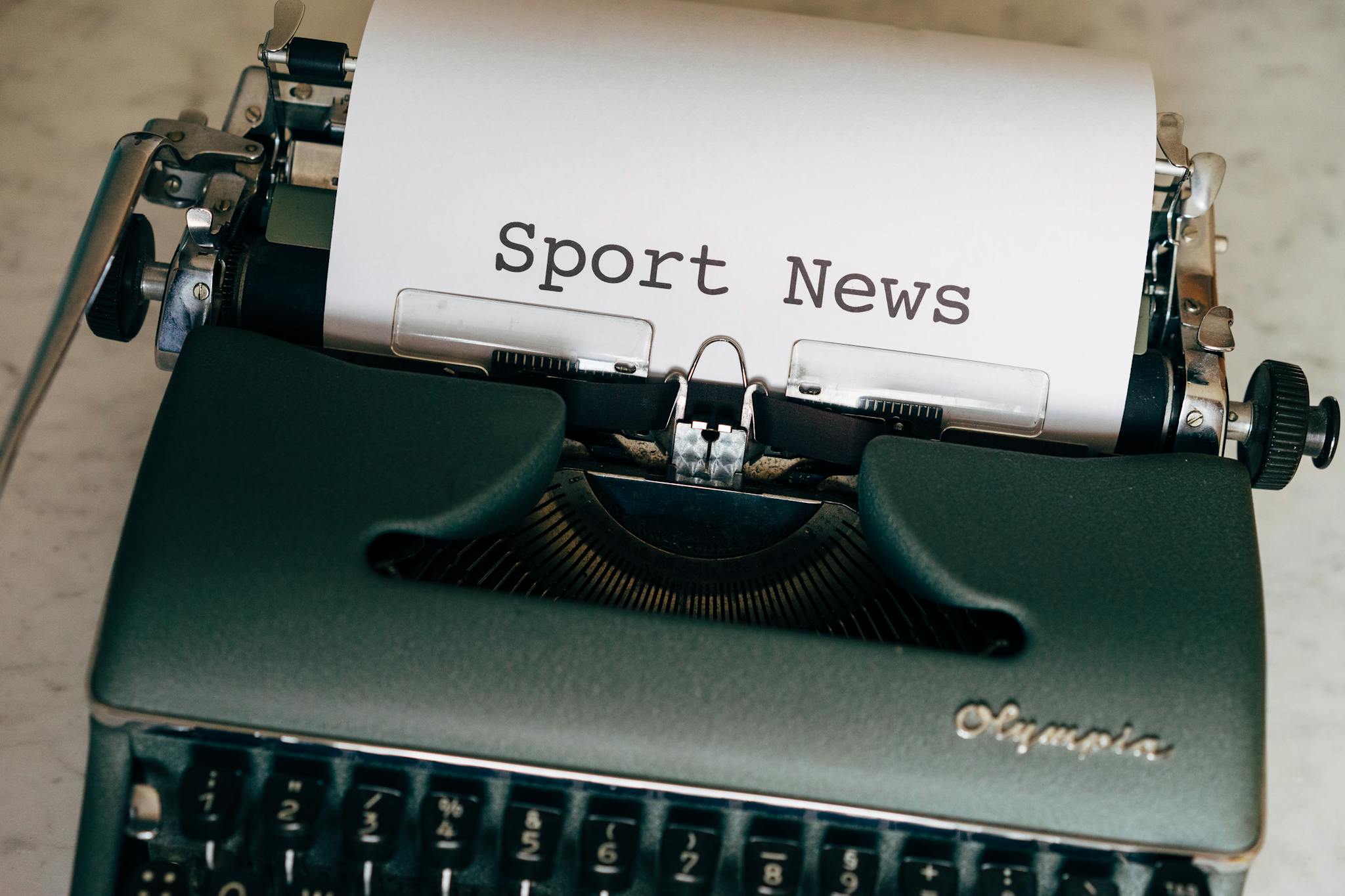 Close-up of a vintage typewriter with a paper showing 'Sport News', evoking nostalgia and classic journalism.