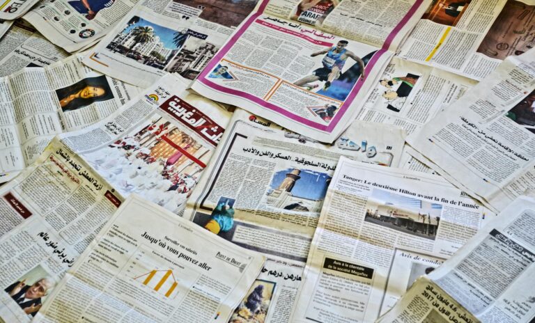 Close-up view of various newspapers laid out, showcasing diverse headlines and articles.
